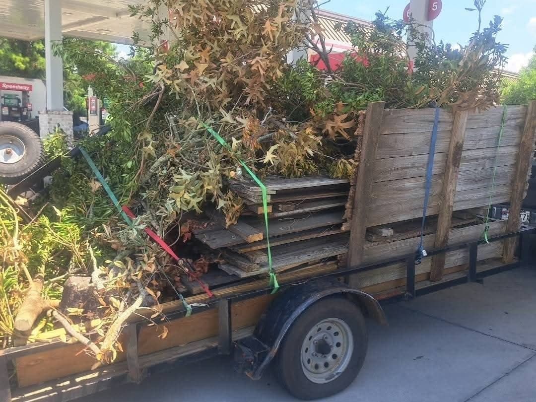 Trailer stacked with cut brush, branches and reclaimed lumber